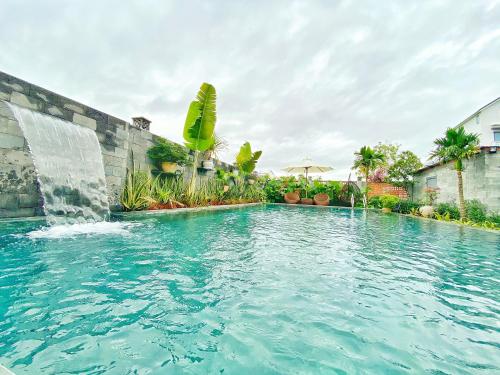a swimming pool with a waterfall and a fountain at Hoi An Cabbage Garden in Hoi An