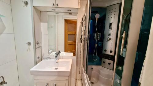 La salle de bains blanche est pourvue d'un lavabo et d'une douche. dans l'établissement Apartament Piękna Katowice, à Katowice
