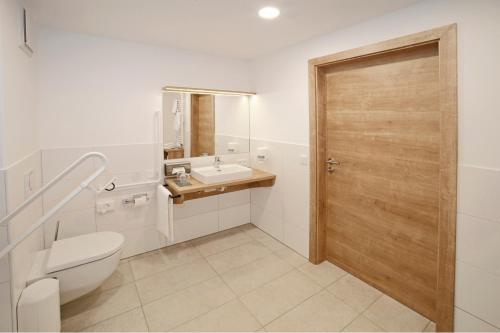 uma casa de banho com um WC, um lavatório e uma porta de madeira em Gasthof Berger em Sankt Peter