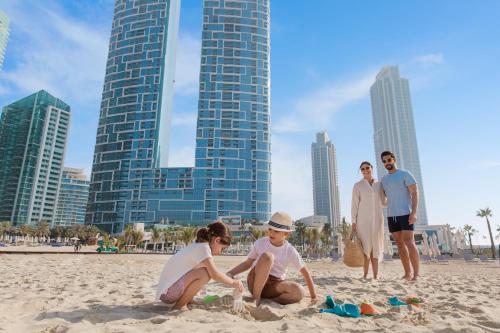 een groep mensen die spelen in het zand op het strand bij Address Beach Resort in Dubai