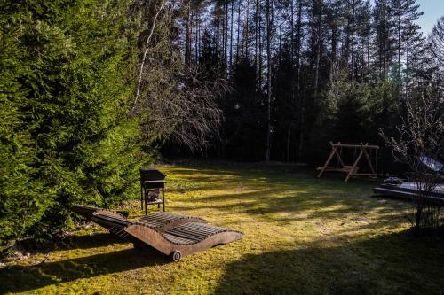 a chair and a bench in a yard at Gilė -'Virš Ąžuolų' - Forest SPA - Horses - Lake - Chalet in Paplatelė