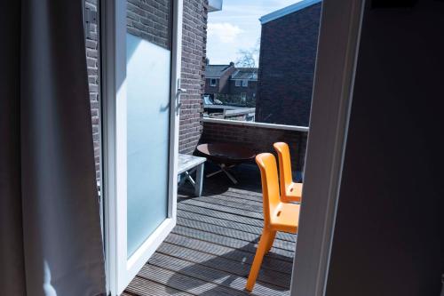 a orange chair sitting on a balcony with a window at HOLT Hotel in Nijmegen