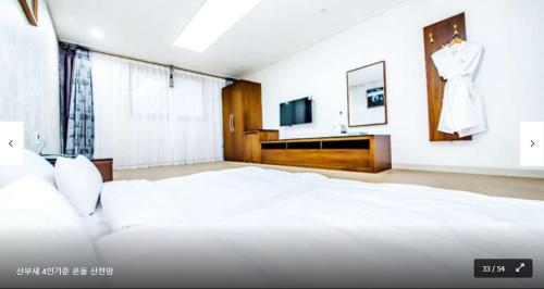 a bedroom with a white bed and a dress in a window at The Stay Century Hotel in Jeju