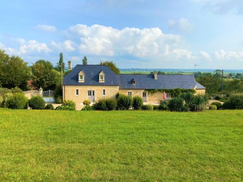 uma casa grande num campo de relva verde em Le domaine des Roseraies em Monfréville