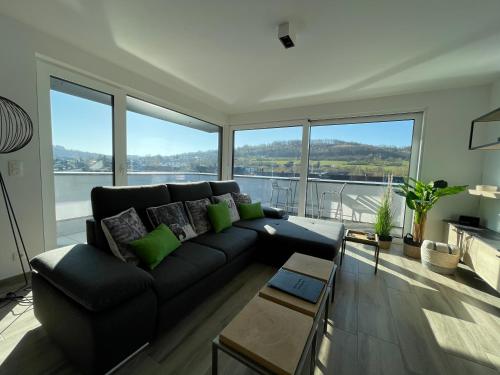 a living room with a black couch and large windows at Penthouse Lebierre in Malmedy