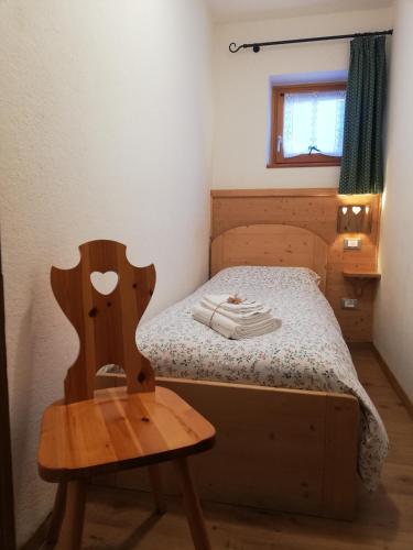 a small bedroom with a bed and a wooden chair at Cesa de Conesel in Colle Santa Lucia