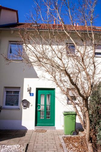 a green door on a white house with a tree at SUNNYHOME Monteurwohnungen und Apartments nahe Regensburg in Obertraubling