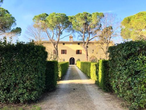 eine Auffahrt zu einem gelben Haus mit Hecken in der Unterkunft Agriturismo Villa Buonsignori in Corsano