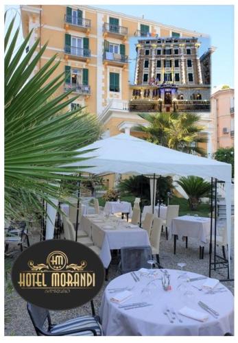 a restaurant with white tables and chairs and a building at Hotel Morandi in Sanremo