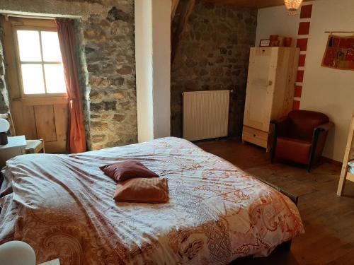 a bedroom with a bed and a chair and a window at Le Marconnès in Saint-Arcons-de-Barges