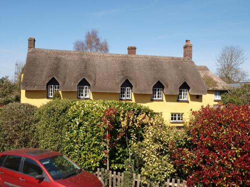 a red car parked in front of a yellow house at Red Lion in Exeter