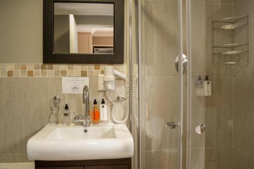 une salle de bain avec un lavabo et une douche avec un miroir dans l'établissement Ruslamere Hotel and Conference Centre, à Durbanville