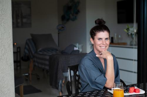 a woman sitting at a table with a plate of food at C' la Vie Luxury Accommodation in Melkbosstrand