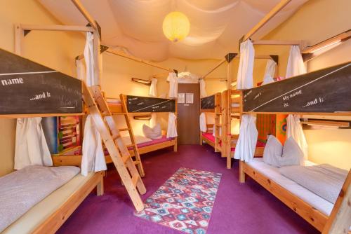 a room with three bunk beds and a rug at Hostel Lollis Homestay Dresden in Dresden