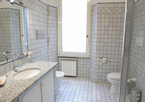 un bagno piastrellato bianco con un water e un lavandino di GH Colosseum a Roma
