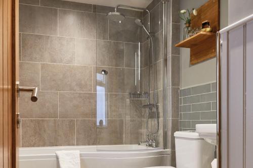 a bathroom with a shower and a toilet and a sink at The Millstone, Mellor in Blackburn