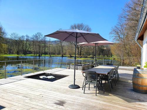 a wooden deck with a table and chairs and an umbrella at Les étangs du Thioux B&B in Malmedy