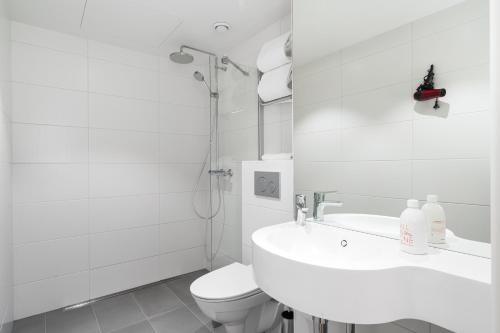 a white bathroom with a toilet and a sink at Omena Hotel Turku Kauppiaskatu in Turku