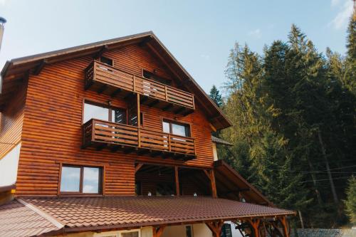 a wooden house with a balcony on top of it at Pensiunea Agnes in Durau
