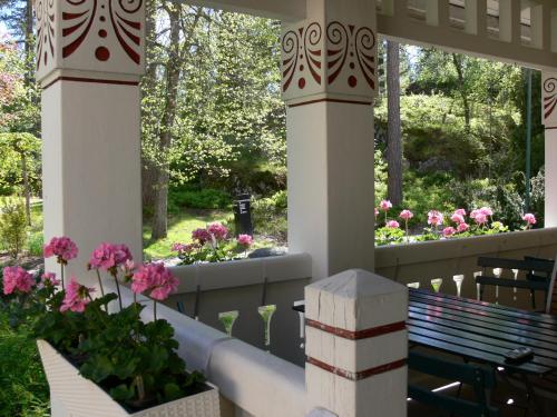 una veranda con fiori rosa e una panchina di Hotelli Tiiliriihi a Espoo