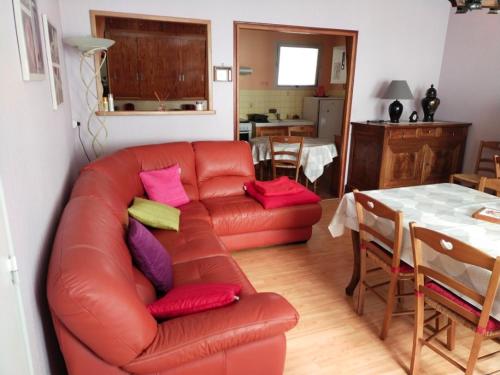 a living room with a red leather couch and a table at Forestier in Marennes