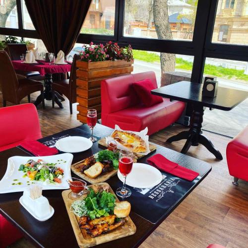 a table with plates of food and glasses of wine at Отель БЕССАРАБИЯ in Izmail