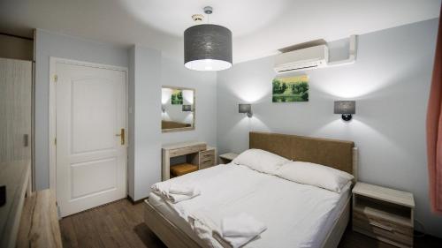 a bedroom with a white bed and a white ceiling at Lux Panzió in Szarvas