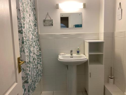 a white bathroom with a sink and a mirror at The Garden Suite in Basingstoke