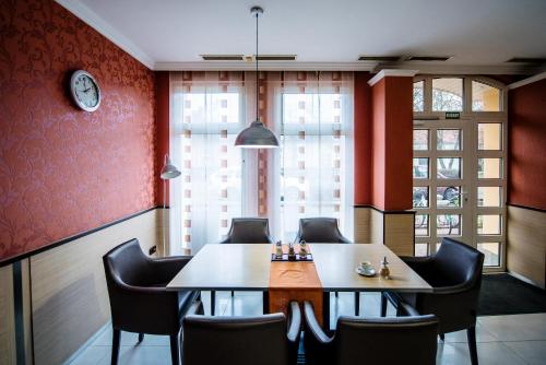a dining room with a table and chairs and a clock at Lux Panzió in Szarvas