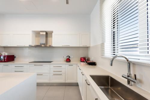 Una cocina blanca con gabinetes blancos y un fregadero. en Seafront Villa Maya by Ruidoso Luxury, en Ayia Napa