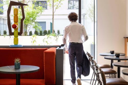a person walking through a restaurant looking out the window at Hotel Le 37 Bis in Neuilly-sur-Seine