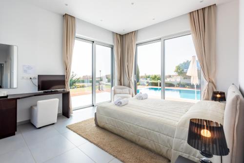 1 dormitorio con 1 cama y TV y algunas ventanas en Seafront Villa Maya by Ruidoso Luxury, en Ayia Napa
