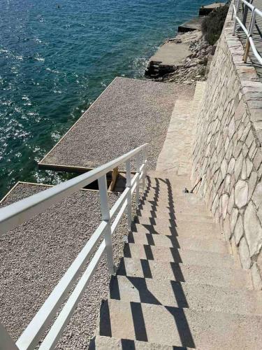 a stairway with a white rail and the ocean at Apartments Lukrecia in Neum