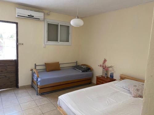 1 dormitorio con 2 camas y ventana en Zimmer Dora, en Neve Zohar