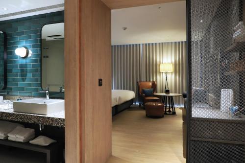 La salle de bains est pourvue d'un lavabo et d'un lit dans la chambre. dans l'établissement Just Sleep Tainan Hushan, à Tainan