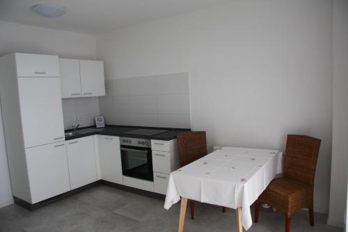 una pequeña cocina con mesa blanca y sillas en C+U Ferienwohnungen en Harthausen
