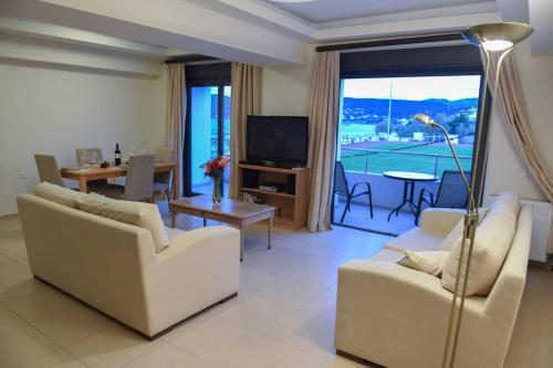 a living room with white furniture and a large window at Dr Vasi Holidays House in Agios Nikolaos