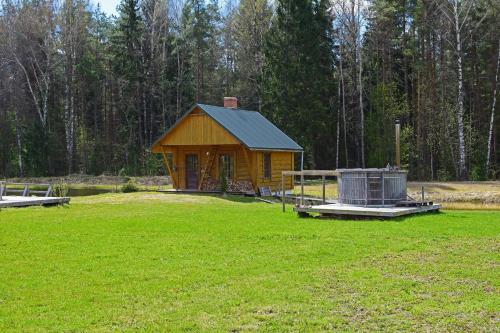 mały drewniany domek na polu trawy w obiekcie Brivdienu maja Ūtkas w mieście Bauņi