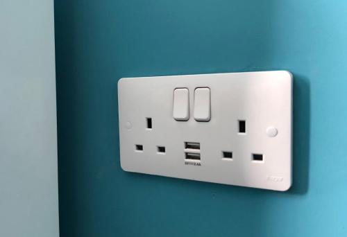 un interruptor de luz blanco en una pared azul en Sidings Holt - whole house sleeps up to 7 en Crewe