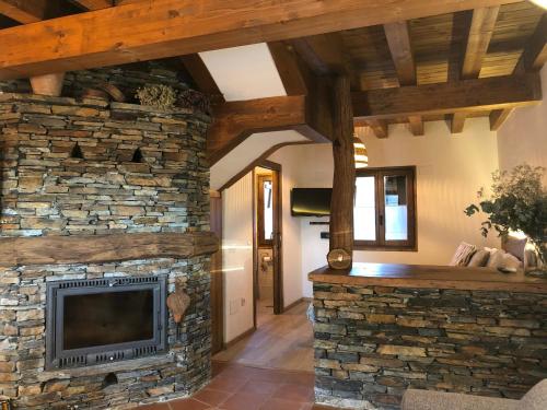 - un salon avec une cheminée en pierre et une télévision dans l'établissement Refugios Del Valle Negro, à Campillo de Ranas