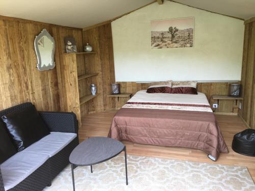 a bedroom with a bed and a couch in it at Glamping Cabana nas arvores in Ponte da Barca