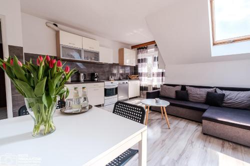 uma cozinha e sala de estar com um vaso de flores sobre uma mesa em Apartament 27 z tarasem em Jelenia Góra