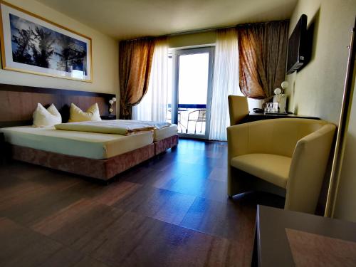 a hotel room with two beds and a chair at Hochwälder Wohlfühlhotel in Losheim