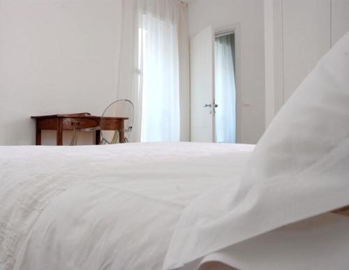 a white bed in a white room with a desk at Locanda Mezzosale in Conegliano