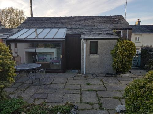 a house with a patio and a table in front of it at Cottage - Sleeps 4 - Pets Ok - Garden - Parking in Carnforth