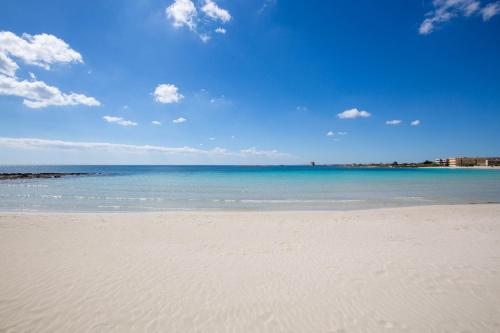 una playa con el océano y un cielo azul en Residence Kalura, en Porto Cesareo