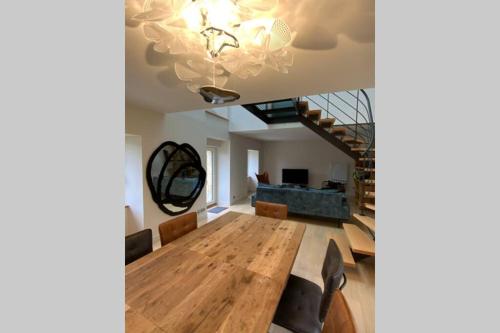a dining room with a wooden table and a chandelier at Maison près de la Pointe du Raz in Plogoff