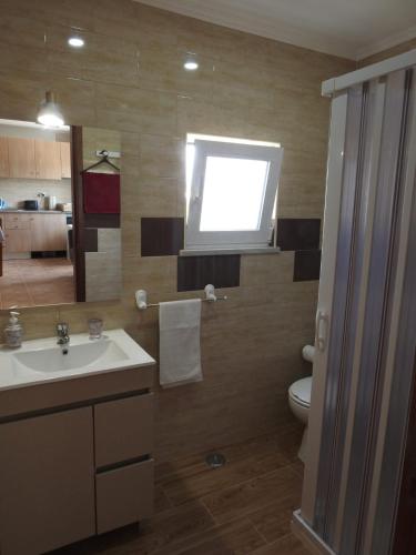 a bathroom with a sink and a toilet and a window at Monte da Vinha Nova in Santiago do Cacém
