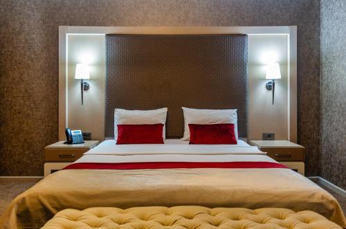 a bedroom with a large bed with two red pillows at Sky Hotel Baku in Baku
