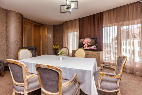 a dining room with a table and chairs and a tv at Sky Hotel Baku in Baku